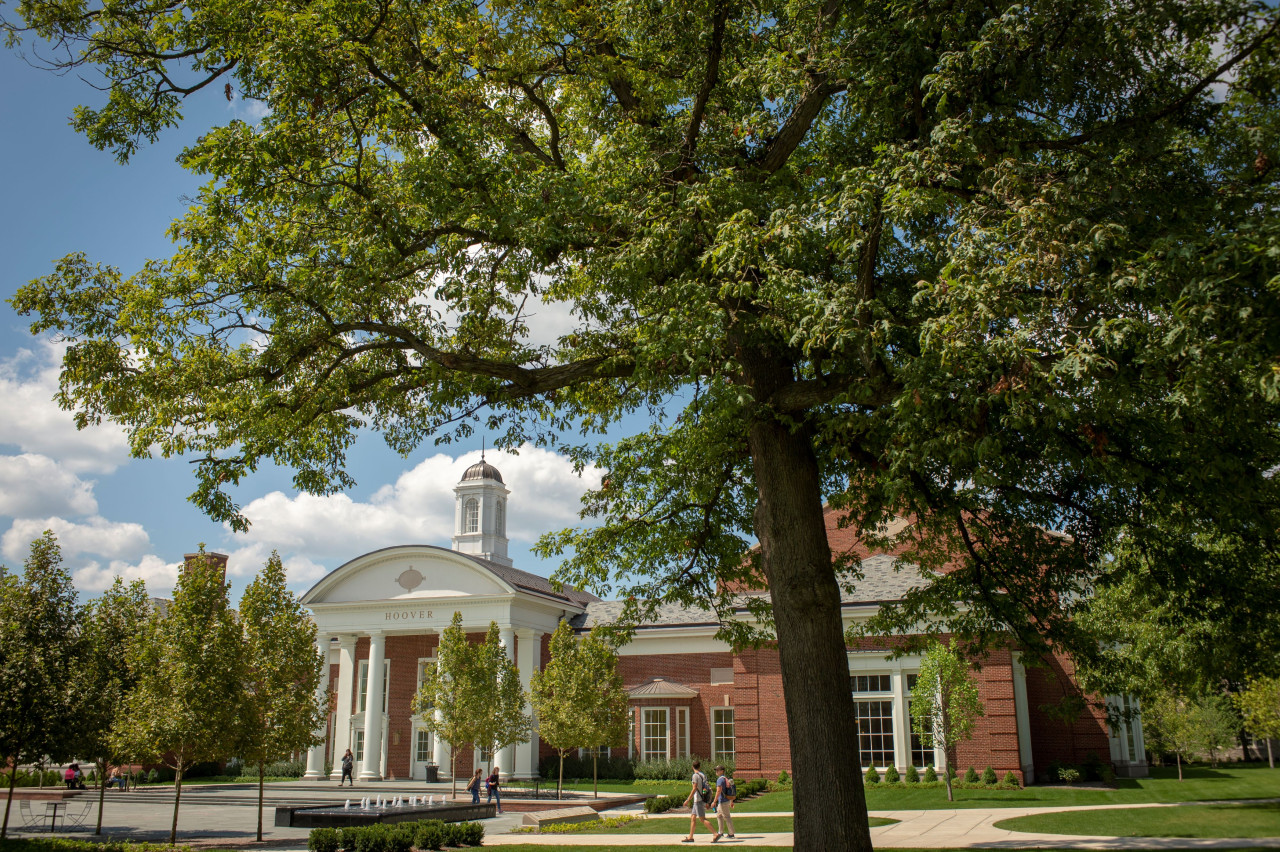 Students walk in front of Hoover Hall, framed by trees.