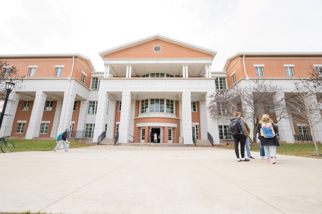 Exterior of Julian building with a group a students standing and chatting in front of the building.