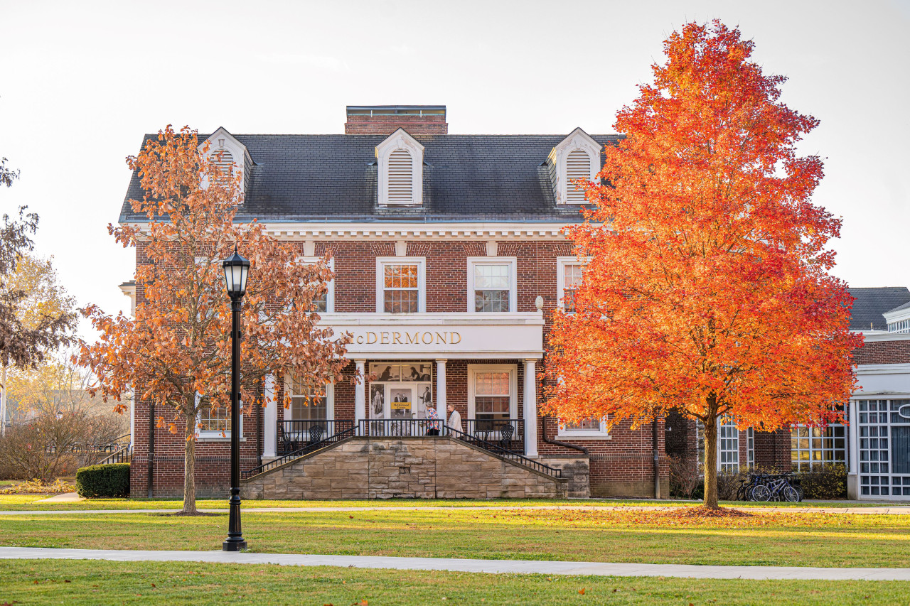 Exterior of McDermond Center building between two trees with orange fall foliage.