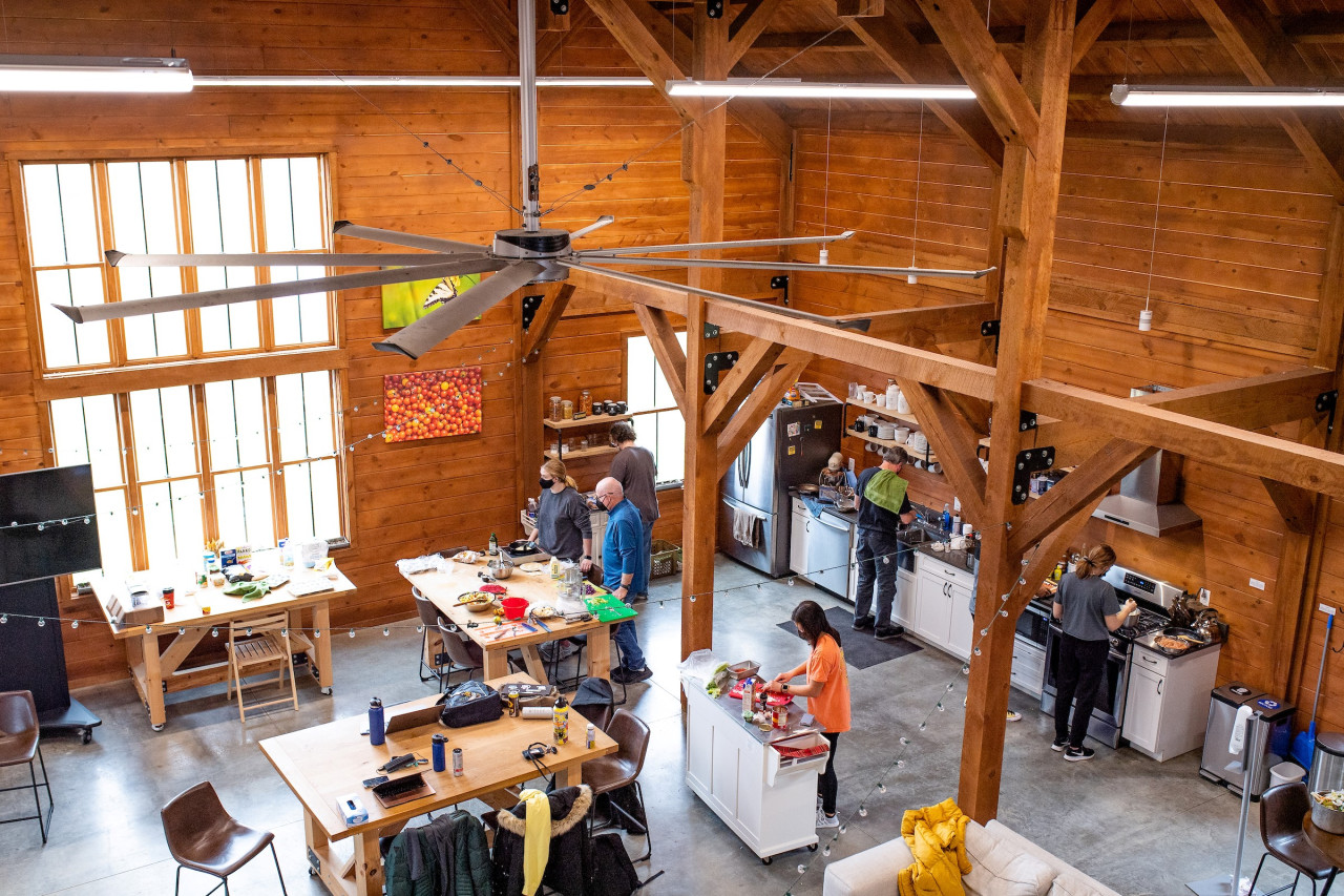 Birds eye view of people preparing food in a large open concept building with wood paneled walls.