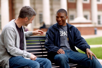 Alumni sitting on a bench visiting