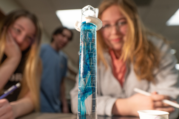Students looking at a beaker with fluid in a lab